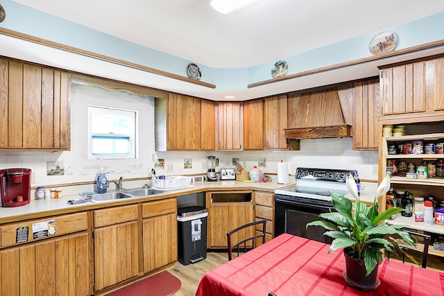 kitchen featuring tasteful backsplash, sink, premium range hood, black electric range, and light wood-type flooring