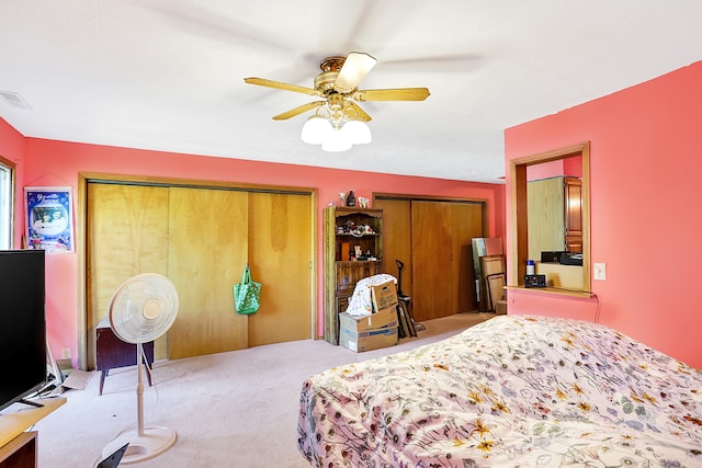 bedroom with multiple closets, carpet flooring, and ceiling fan