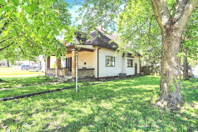 view of front of property with a chimney, central AC unit, and a front yard