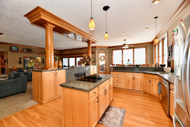 kitchen featuring black electric stovetop, light carpet, decorative columns, hanging light fixtures, and sink