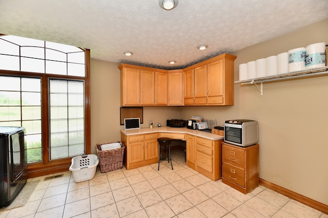 tiled office space featuring washer / dryer, built in desk, and a textured ceiling