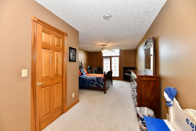 carpeted bedroom with ceiling fan and a textured ceiling