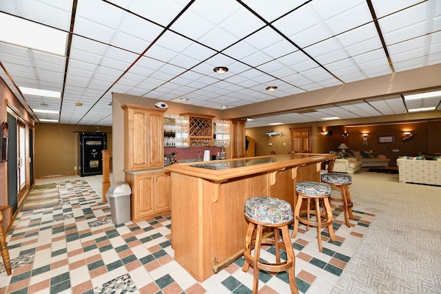 kitchen with a kitchen bar, light brown cabinetry, light tile flooring, and kitchen peninsula