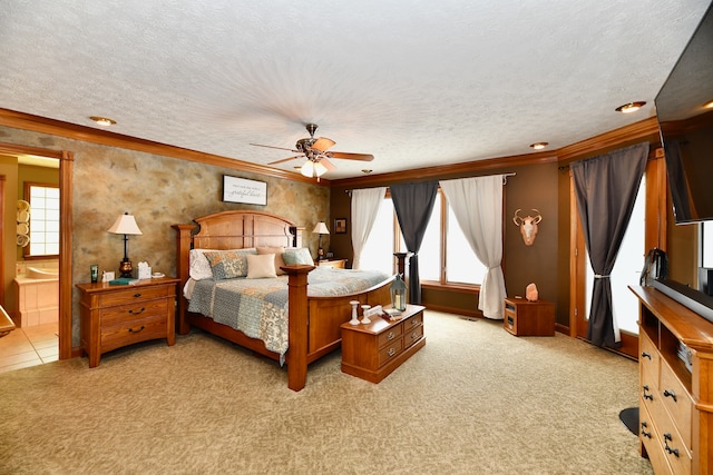 bedroom featuring ceiling fan, crown molding, light colored carpet, connected bathroom, and a textured ceiling