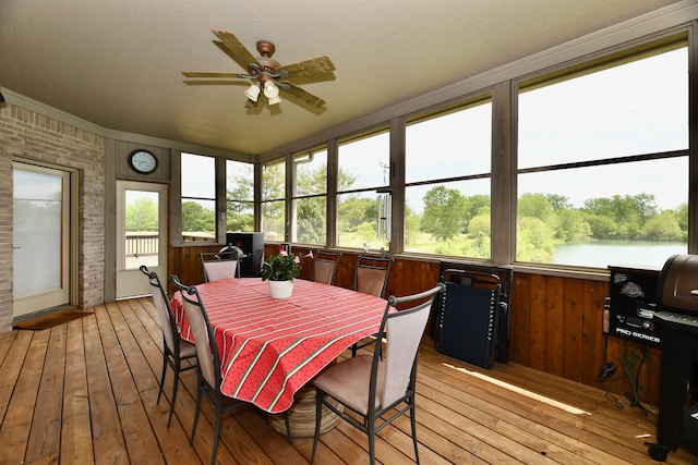 sunroom / solarium featuring ceiling fan and a water view