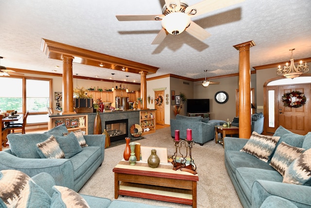 carpeted living room with crown molding, a textured ceiling, ornate columns, and ceiling fan with notable chandelier