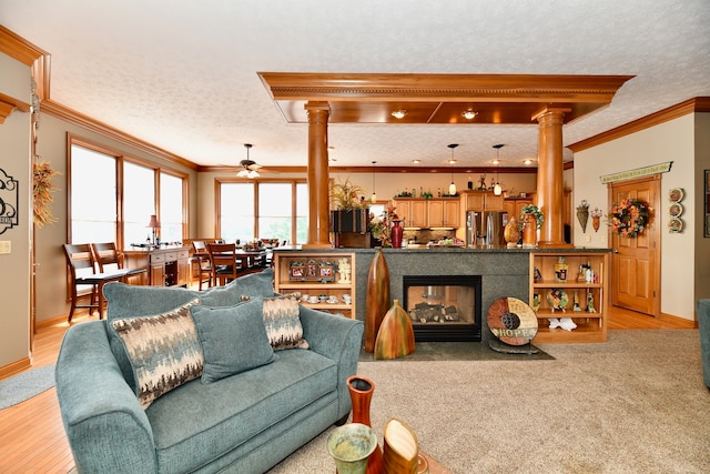 carpeted living room with ornate columns, a multi sided fireplace, a textured ceiling, and crown molding