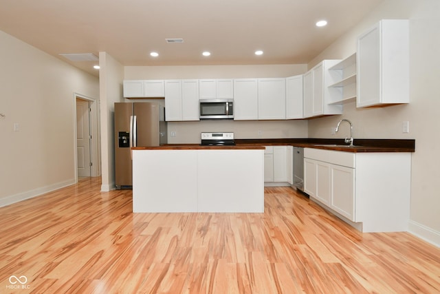 547 Udell St, Indianapolis, IN 46208 - kitchen with stainless steel appliances, a sink, open shelves, light wood-type flooring, and white cabinets