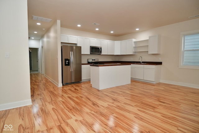 547 Udell St, Indianapolis, IN 46208 - kitchen with appliances with stainless steel finishes, open shelves, light wood-type flooring, a sink, and white cabinetry