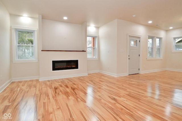547 Udell St, Indianapolis, IN 46208 - unfurnished living room with light wood-style flooring, a glass covered fireplace, plenty of natural light, and recessed lighting