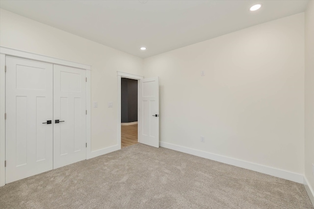 unfurnished bedroom featuring light colored carpet and a closet