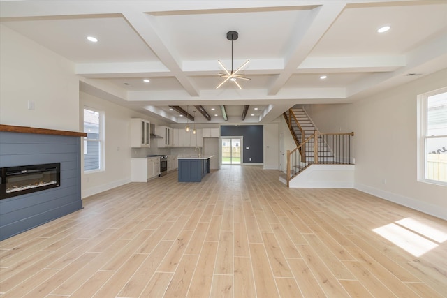 unfurnished living room with light wood-type flooring, beam ceiling, a chandelier, and coffered ceiling