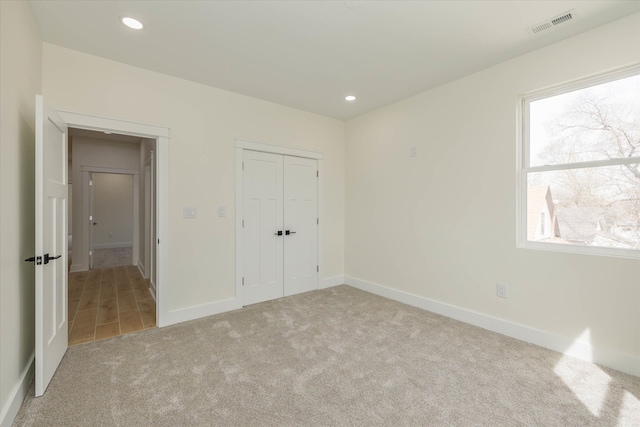 unfurnished bedroom featuring a closet and light colored carpet