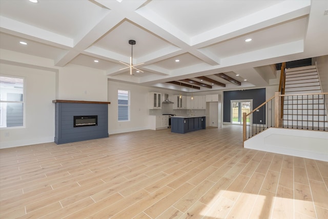 unfurnished living room featuring coffered ceiling, light hardwood / wood-style floors, and beam ceiling