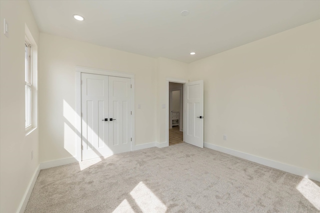 unfurnished bedroom with a closet and light carpet