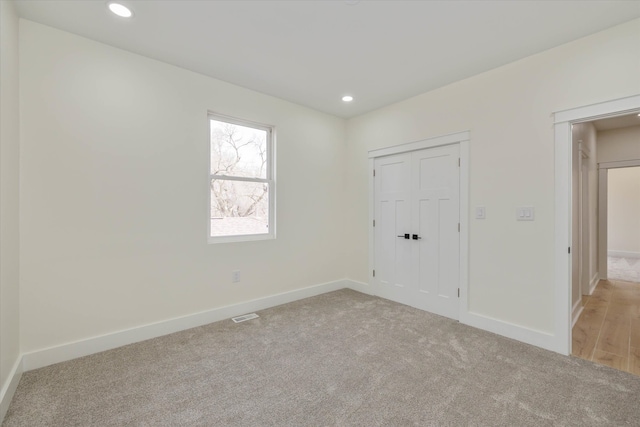 unfurnished bedroom with a closet and light colored carpet