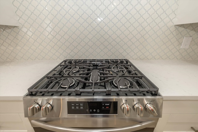 details with stainless steel range with gas stovetop, light stone counters, and decorative backsplash