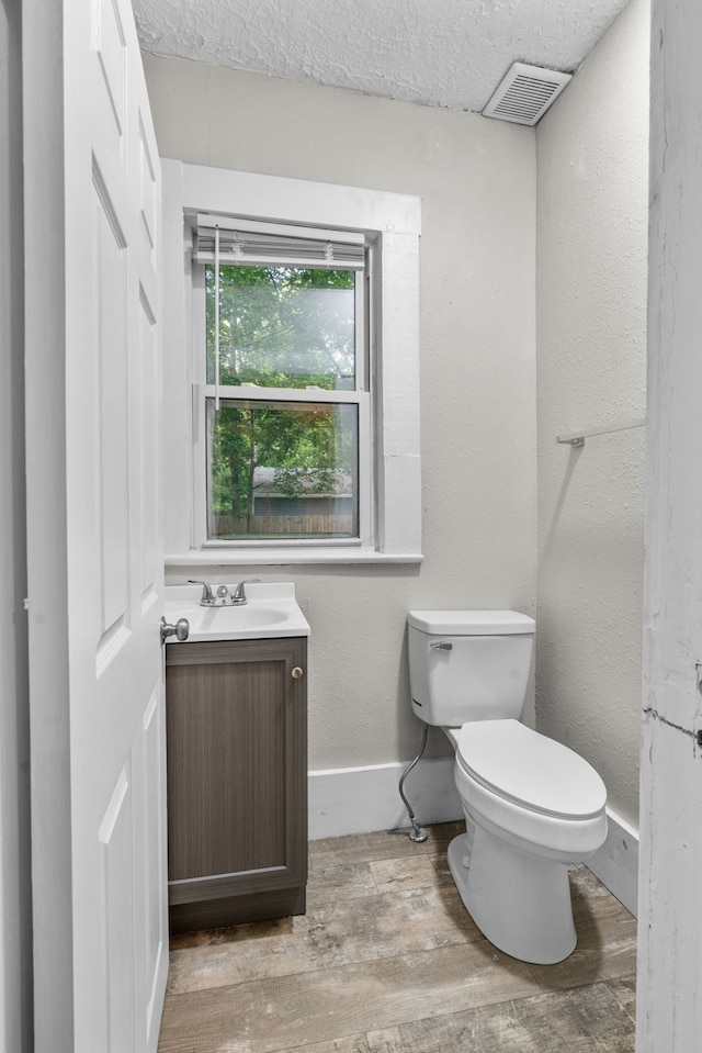 bathroom featuring hardwood / wood-style flooring, toilet, vanity, and a textured ceiling