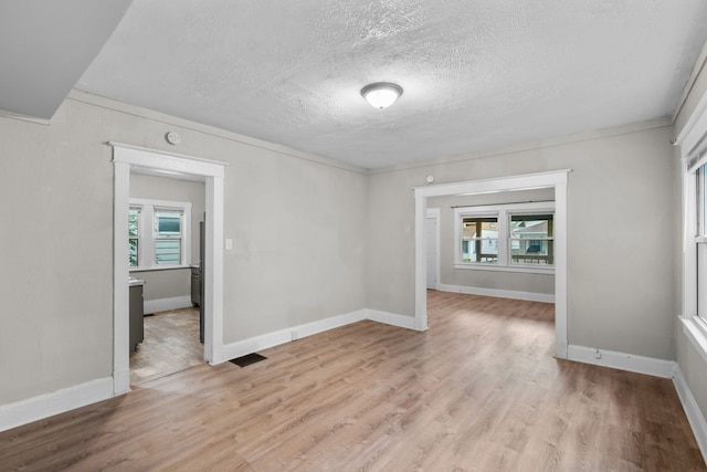 unfurnished room featuring a textured ceiling and light hardwood / wood-style floors