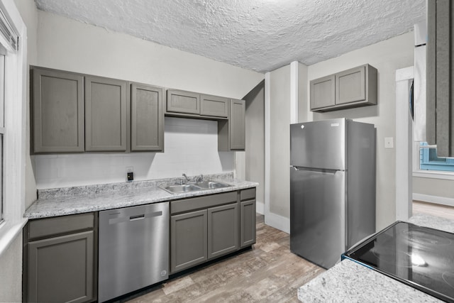 kitchen with gray cabinets, sink, stainless steel appliances, and light wood-type flooring