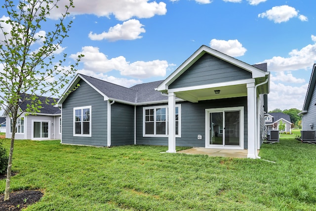 rear view of property featuring a yard and central air condition unit