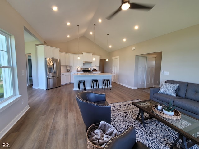 living room with wood-type flooring, high vaulted ceiling, and ceiling fan