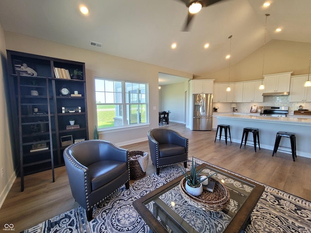 living room with ceiling fan, high vaulted ceiling, and hardwood / wood-style flooring