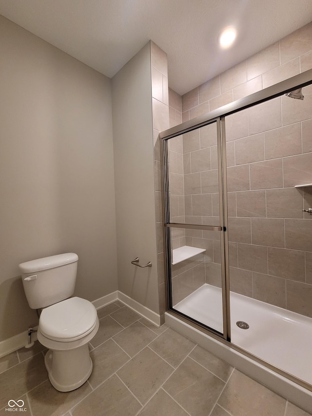 bathroom featuring tile patterned floors, toilet, and a shower with door