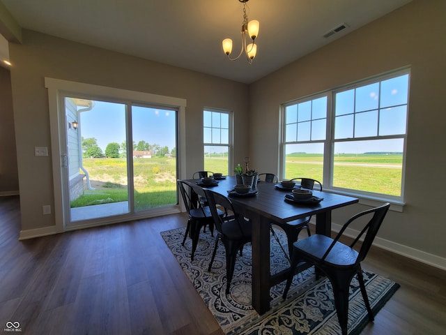 dining area featuring a healthy amount of sunlight, dark hardwood / wood-style flooring, and an inviting chandelier