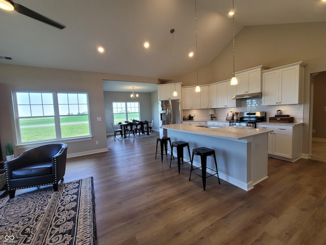 kitchen with dark hardwood / wood-style flooring, stainless steel appliances, white cabinetry, high vaulted ceiling, and a kitchen island