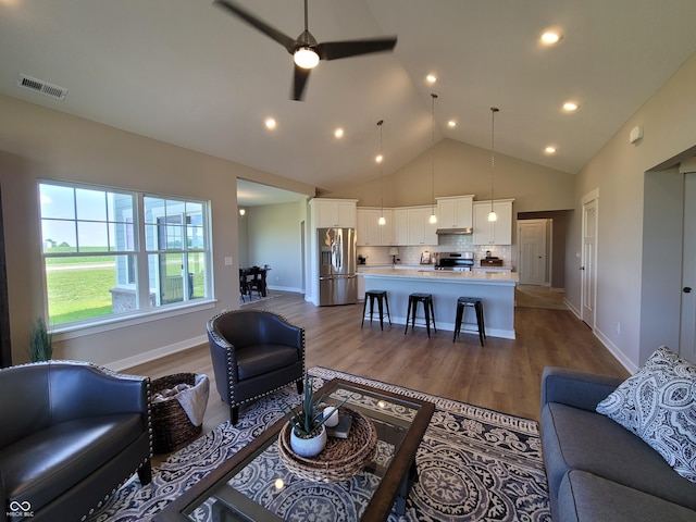 living room with hardwood / wood-style flooring, ceiling fan, and high vaulted ceiling