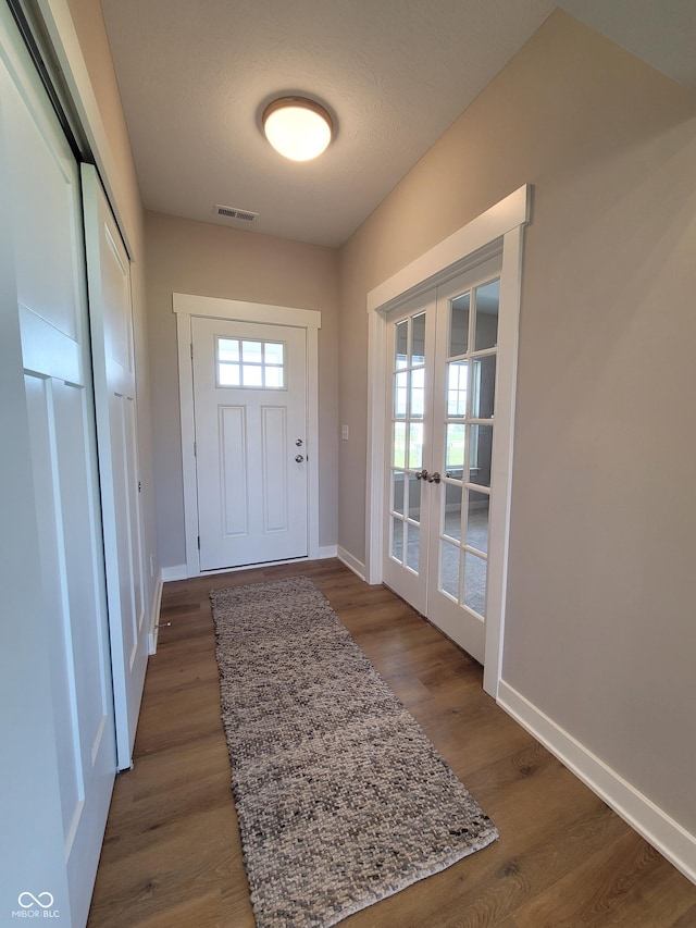 doorway with french doors, dark wood-type flooring, and a textured ceiling