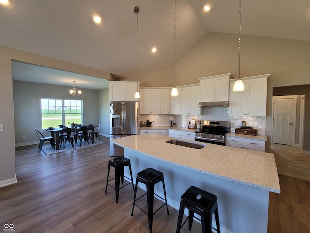 kitchen featuring white cabinets, stainless steel appliances, a breakfast bar area, and an island with sink