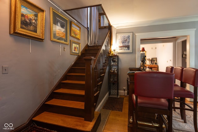 stairway with hardwood / wood-style floors and crown molding