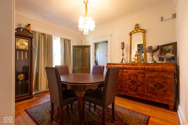 dining room with a chandelier, hardwood / wood-style floors, and crown molding