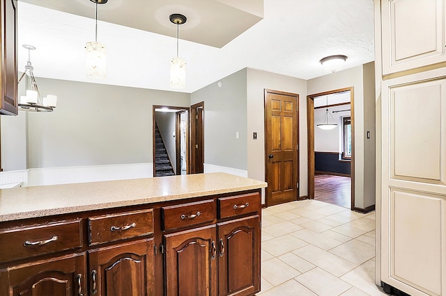 kitchen with dark brown cabinets, decorative light fixtures, a textured ceiling, and light tile patterned floors