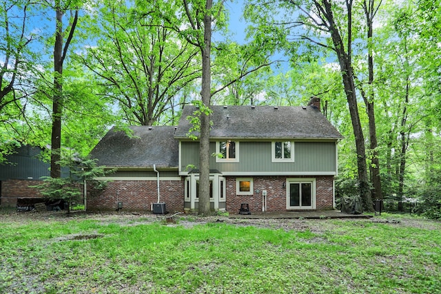 rear view of house featuring cooling unit and a lawn