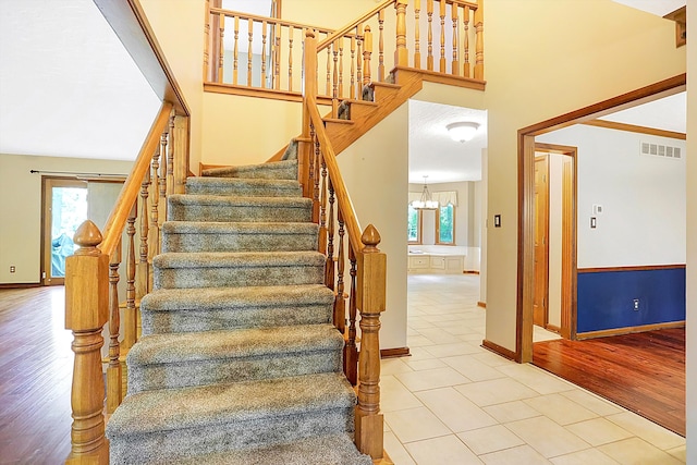 stairway with hardwood / wood-style flooring, a wealth of natural light, and a high ceiling