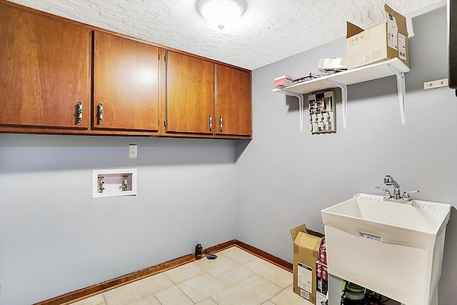 laundry room with light tile patterned floors, sink, hookup for a washing machine, cabinets, and a textured ceiling