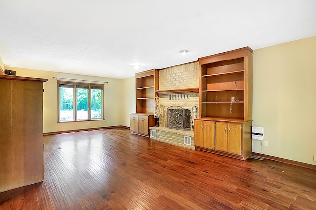 unfurnished living room with a brick fireplace and hardwood / wood-style flooring