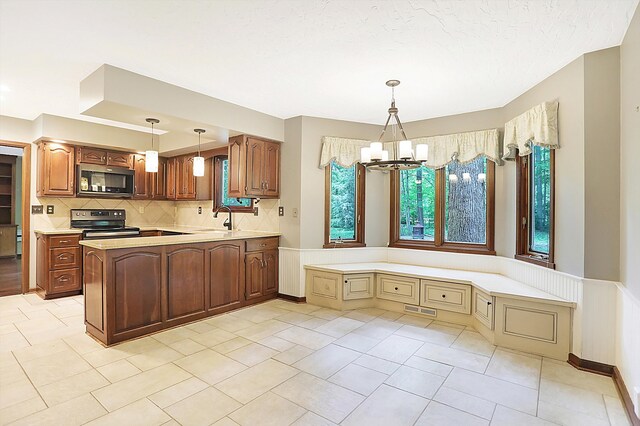 kitchen with sink, an inviting chandelier, stainless steel appliances, decorative light fixtures, and kitchen peninsula