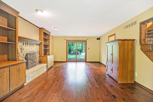 unfurnished living room featuring dark wood-type flooring, a textured ceiling, and a fireplace