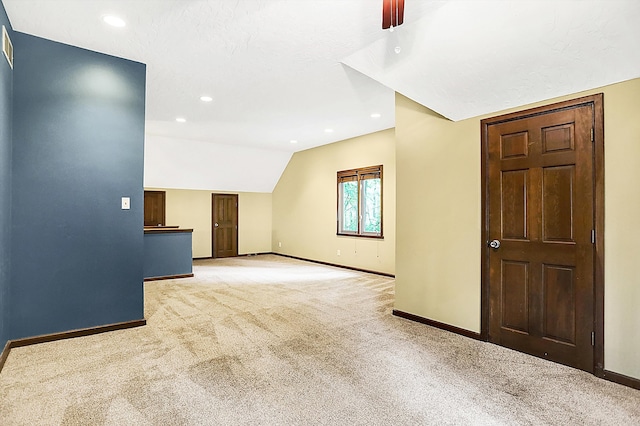 empty room featuring vaulted ceiling, light carpet, and a textured ceiling