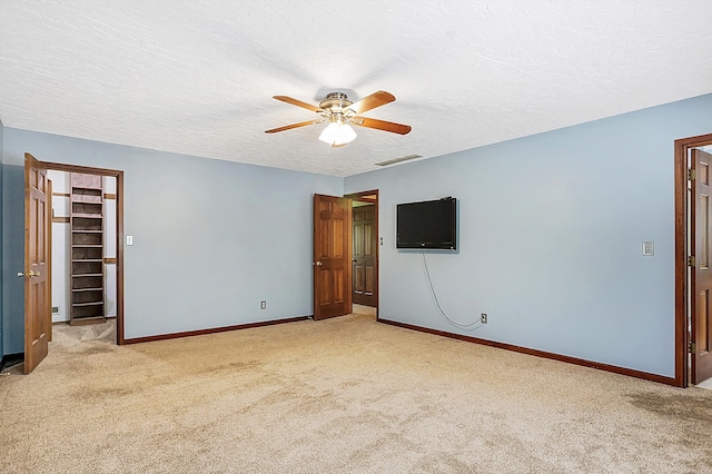 empty room with light carpet, a textured ceiling, and ceiling fan