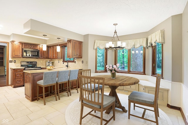 dining area with an inviting chandelier, sink, and a textured ceiling