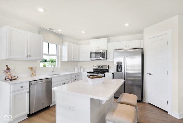 kitchen featuring a kitchen bar, appliances with stainless steel finishes, sink, white cabinets, and a center island