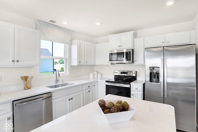 kitchen featuring appliances with stainless steel finishes, white cabinetry, and sink