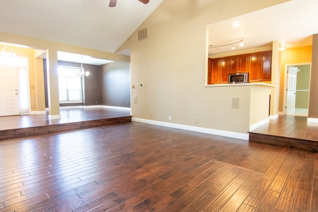 unfurnished living room with high vaulted ceiling, rail lighting, ceiling fan with notable chandelier, and hardwood / wood-style floors