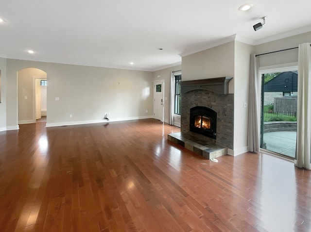 unfurnished living room featuring a tiled fireplace, hardwood / wood-style flooring, and ornamental molding