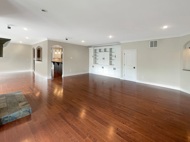 unfurnished living room with dark wood-type flooring, built in shelves, and ornamental molding